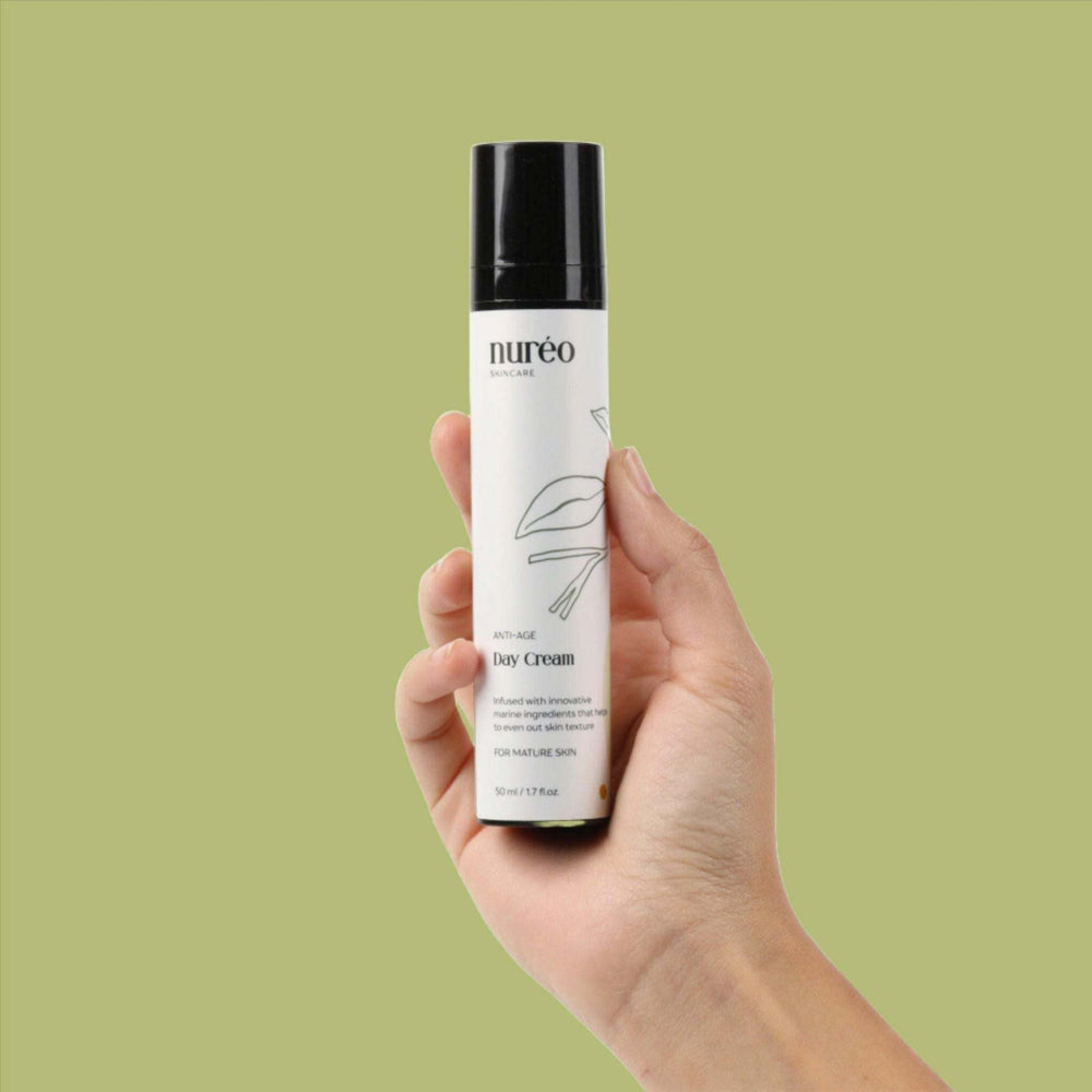 GlowGuard Anti-Aging Cream in a hand against a green background.