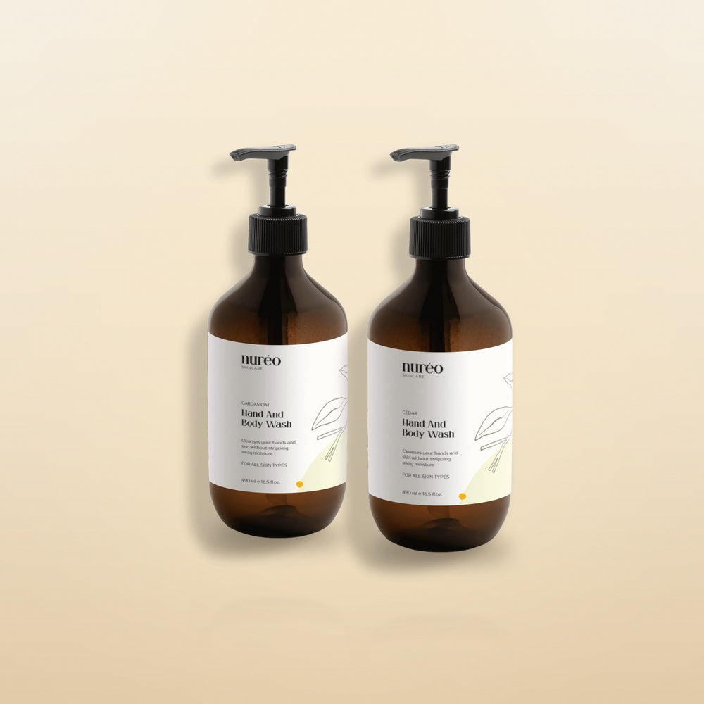 nureo Cedar and Cardamom Hand and Body Wash bundle, two amber pump bottles on warm golden studio background