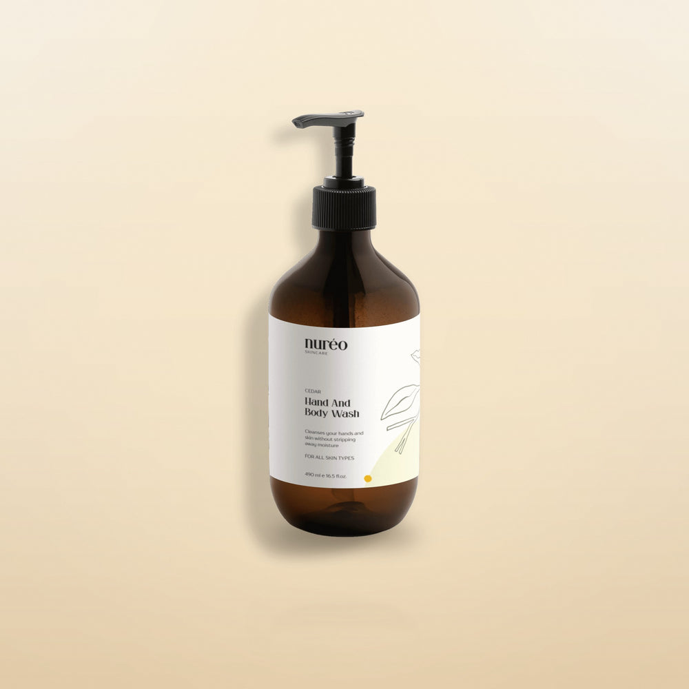 nureo Cedar Hand and Body Wash, amber glass pump bottle on warm golden studio background