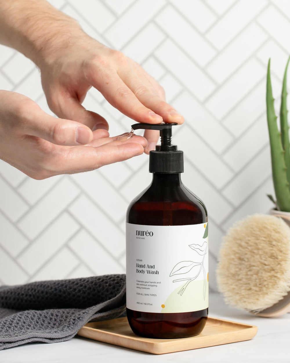 nuréo Cedar Hand and Body Wash, 490ml, held to show scale