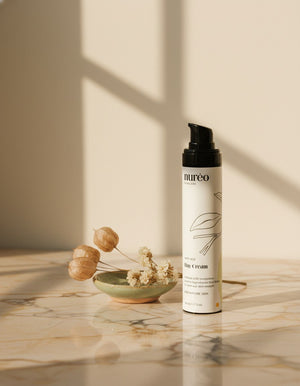 nureo GlowGuard Anti-Aging Day Cream on marble with dried flowers